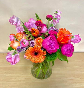 Hot pink peonies, orange gerberas, peach roses, orange tulips, pink sweet in a clear concave vase. Ready for delivery or pick up in Houston.