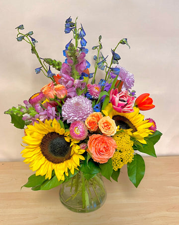 Colorful mix of seasonal flowers like sunflowers, tulips, snapdragons, spray roses in a medium ideal for a Birthday gift in Houston.