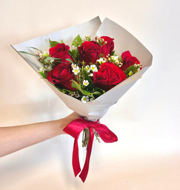 Six premium red roses with fresh greenery wrapped delicately in floral paper with a silk red ribbon. Perfect anniversary gift pickup Houston.