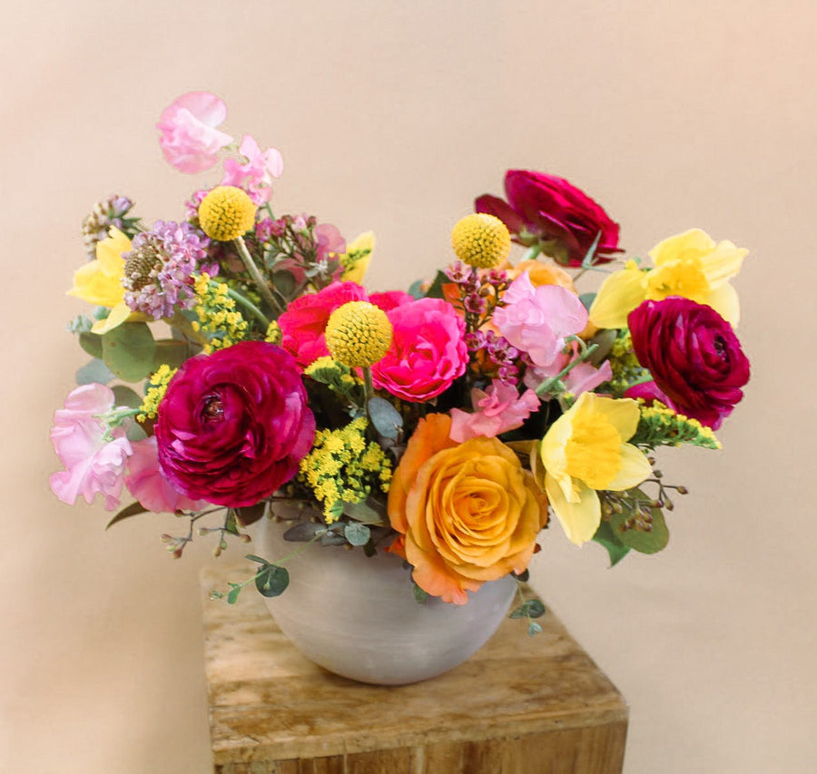 Moody with vibrant colors, burgundy  ranunculus, orange roses, sweet peas, pink scabiosa  in a ceramic gray vase. Premium Flowers Delivery in Houston