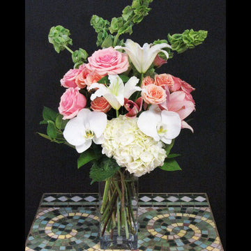 White Phalaenopsis, hydrangea, pink lilie, roses, and more in a tall square vase same day delivery in Houston.