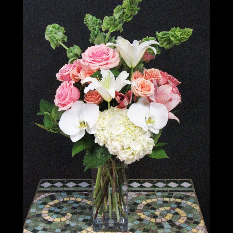 White Phalaenopsis, hydrangea, pink lilie, roses, and more in a tall square vase same day delivery in Houston.