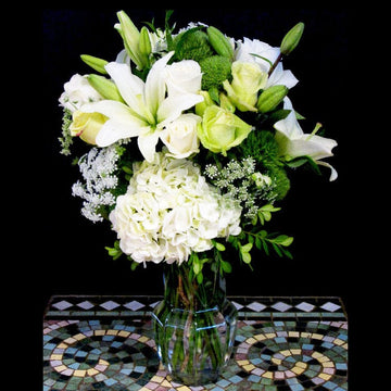 White hydrangea, lilies, roses white flowers in a medium vase; flowers for your wedding anniversary.