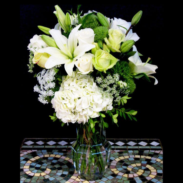 White hydrangea, lilies, roses white flowers in a medium vase; flowers for your wedding anniversary.