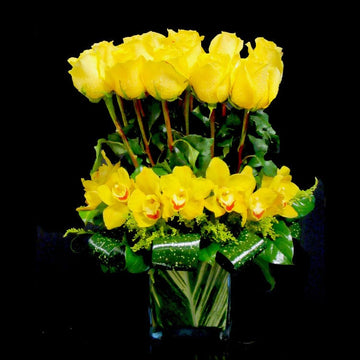 Morden design with yellow roses and cymbidium orchid in square vase with a green leaf wrapped. Birthday flowers in Houston. Available for pick up or delivery in Houston .