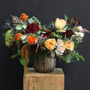 This fall arrangement featuring a variety of flowers including orange, burgundy, and green colors, in a bronze ceramic vase. Thanksgiving, birthdays or just because delivery today in Houston.