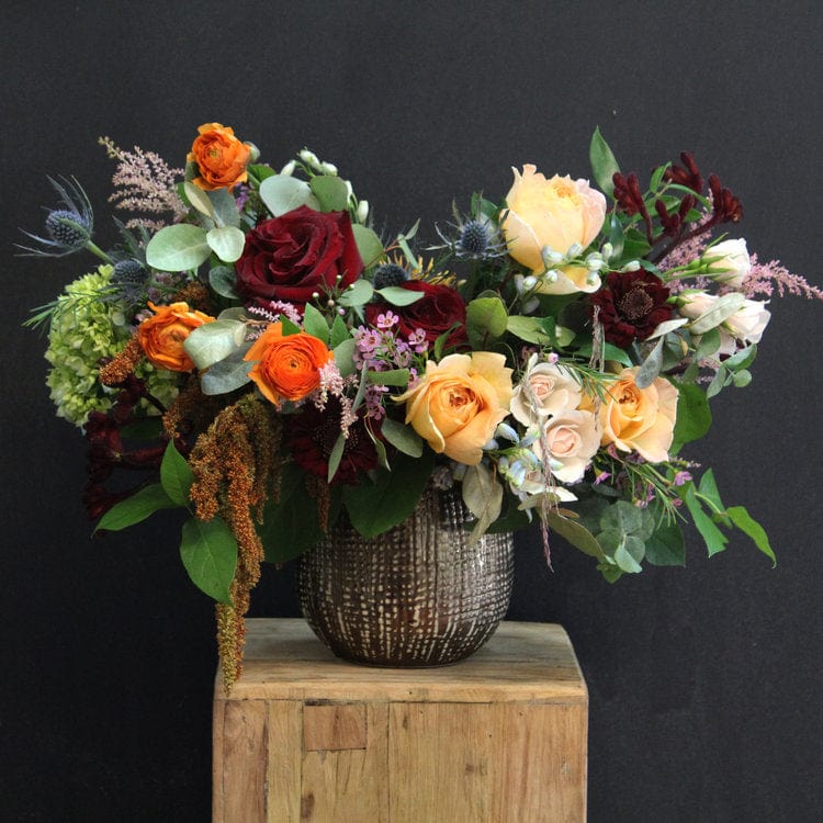This fall arrangement featuring a variety of flowers including orange, burgundy, and green colors, in a bronze ceramic vase. Thanksgiving, birthdays or just because delivery today in Houston.