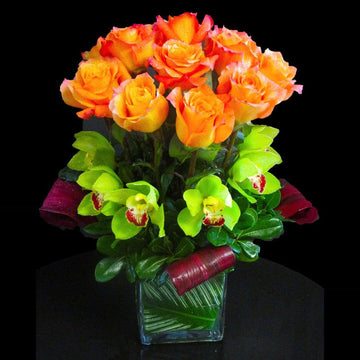 A modern design with orange kissed' roses, green cymbidium orchids in a cube
