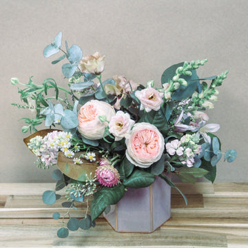 Pink flowers arrangment with garden roses, ranunculus, snapdragons, stock, and lisianthus in a pink hexagon vase. Available for delivery or pickup in Housto.