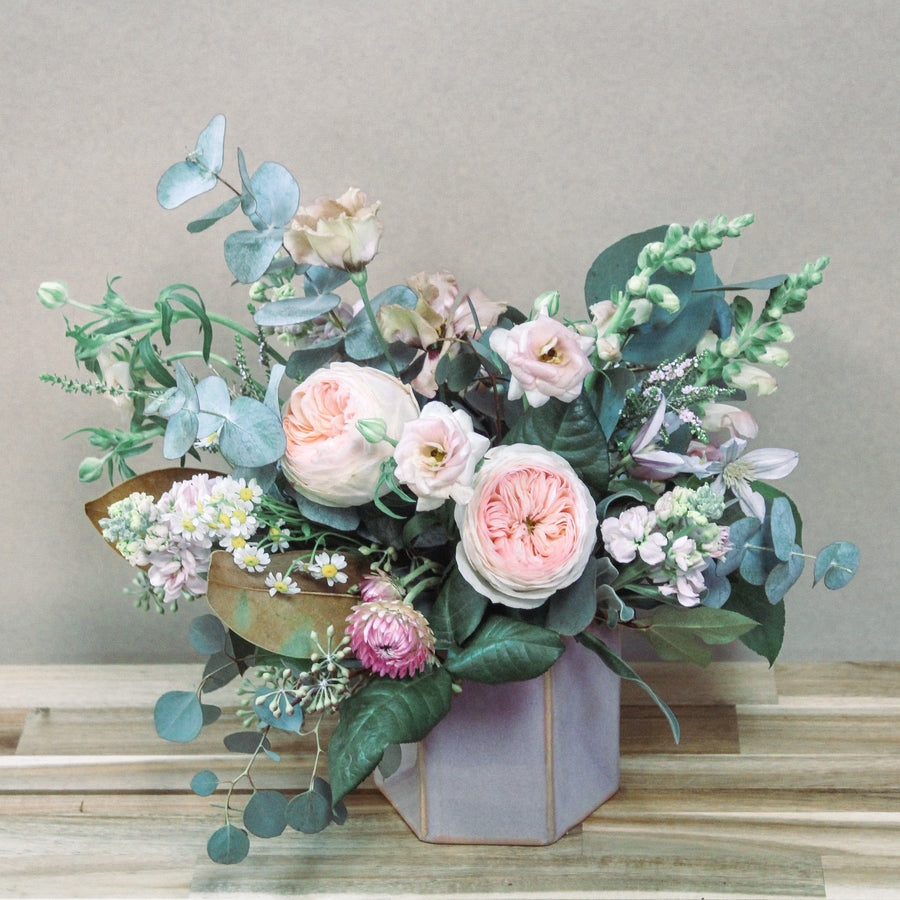 Pink flowers arrangment with garden roses, ranunculus, snapdragons, stock, and lisianthus in a pink hexagon vase. Available for delivery or pickup in Housto.