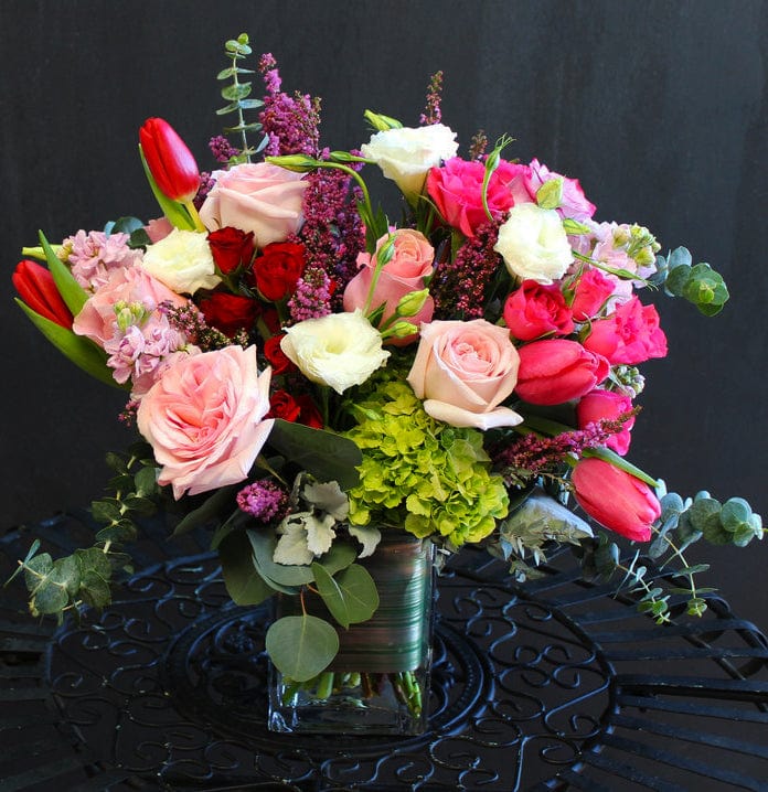 Valentine arrangement with hot pink tulips, pink roses, lisianthus, green hydrangeas, and other mixed foliage in a rectangular vase. Valentine's day, anniversary, birthdays in February. Same day delivery or pick-up in Houston Heights